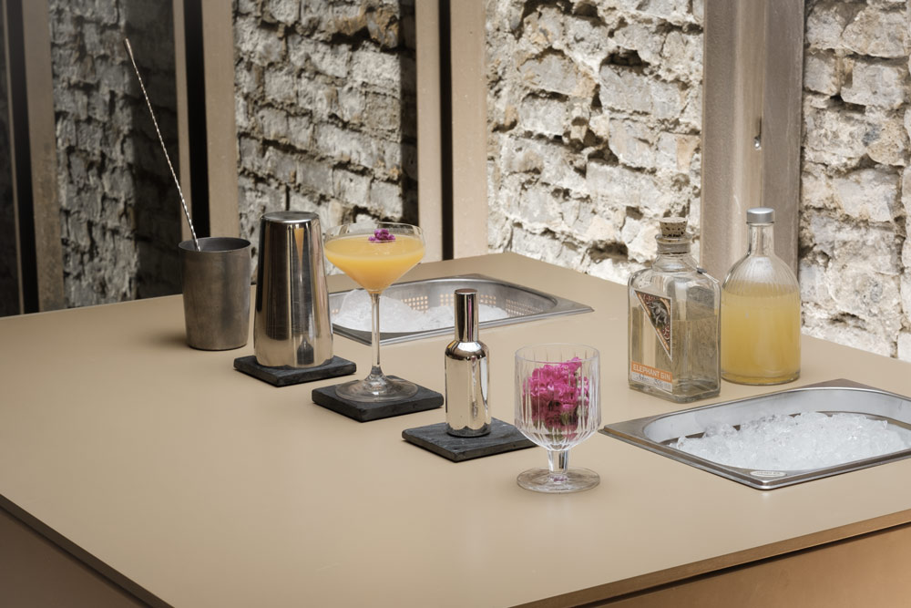 Moderne mobile Cocktailbar mit professionellem Barkeeper-Equipment, Cocktailgläsern und Barzubehör vor Steinwand