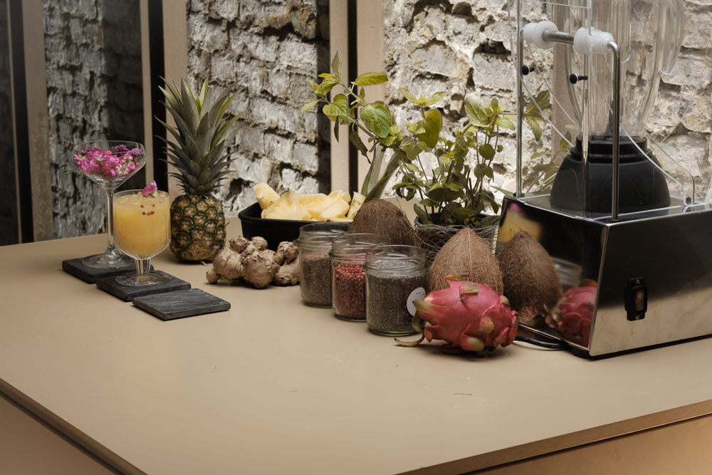 Mobile Cocktailbar mit tropischen Früchten, Ananas, Kokosnüssen, Dragonfruit und Gewürzen auf beiger Arbeitsplatte