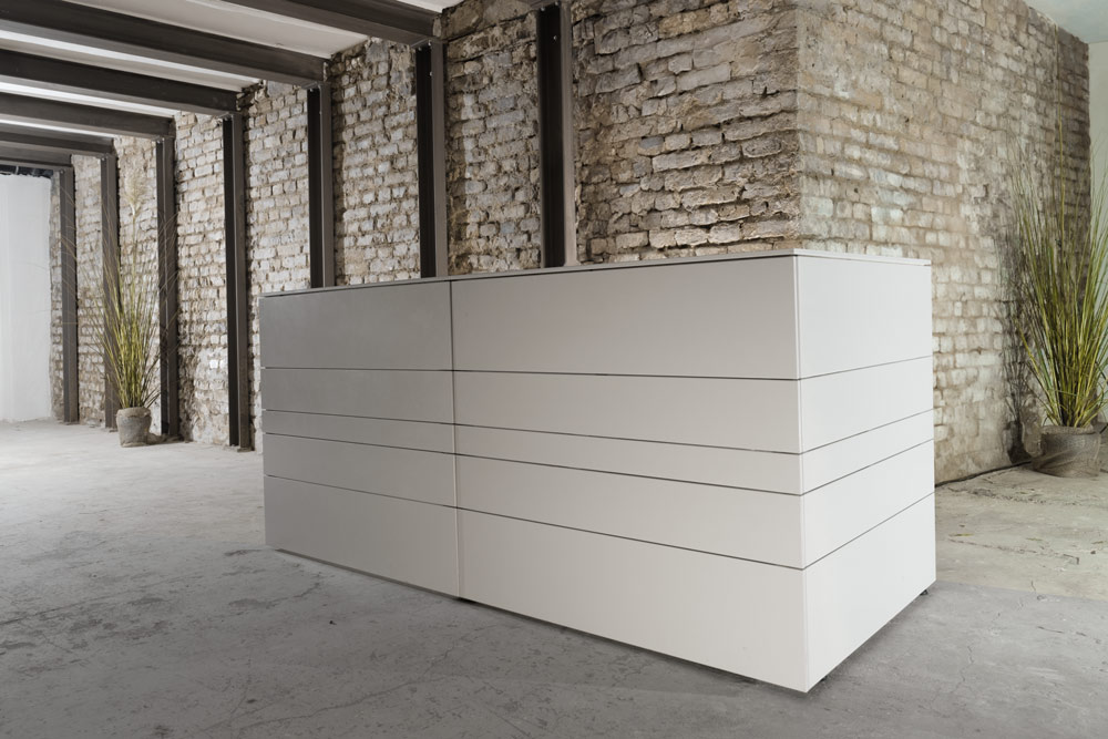 Moderne weiße mobile Bar in minimalistischem Design vor rustikaler Backsteinwand in industriellem Loft-Ambiente