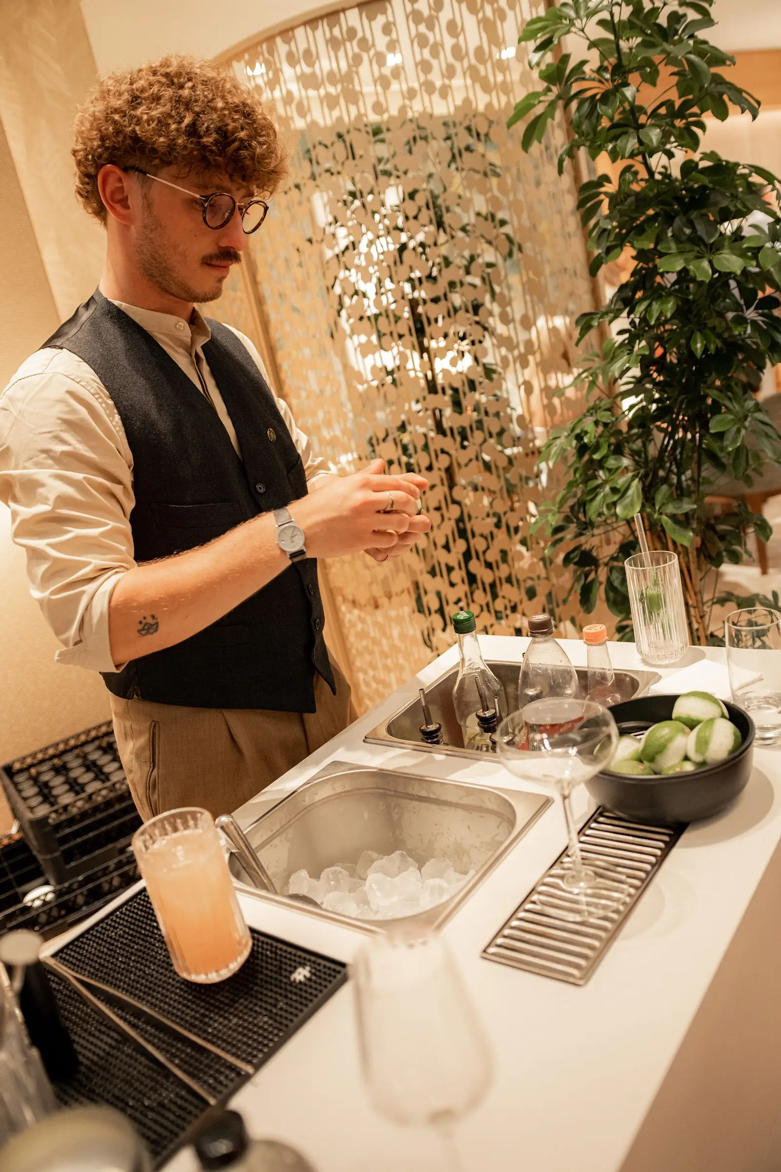 Fertiger heller Cocktail auf der Theke bei einem Event in Wien, dahinter der Barkeeper in Unschärfe