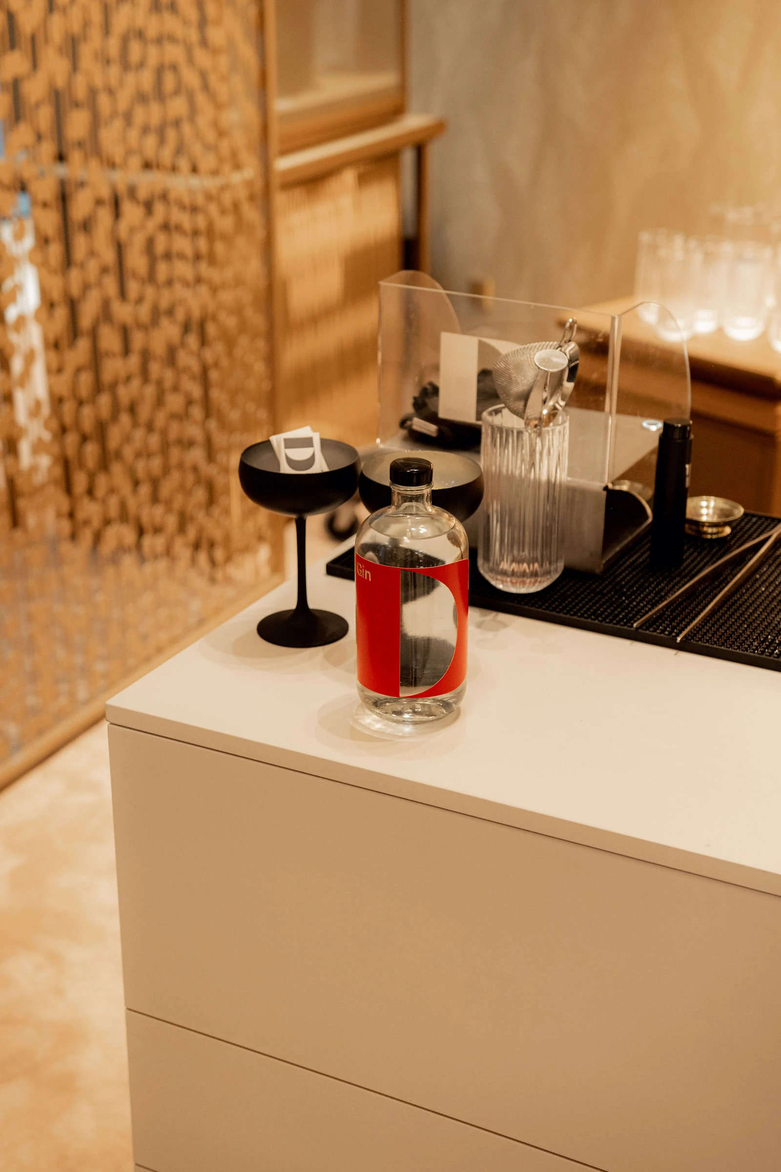 Coupette-Gläser neben einer Karaffe und einer Flasche mit Branding beim Cocktail Catering in Wien