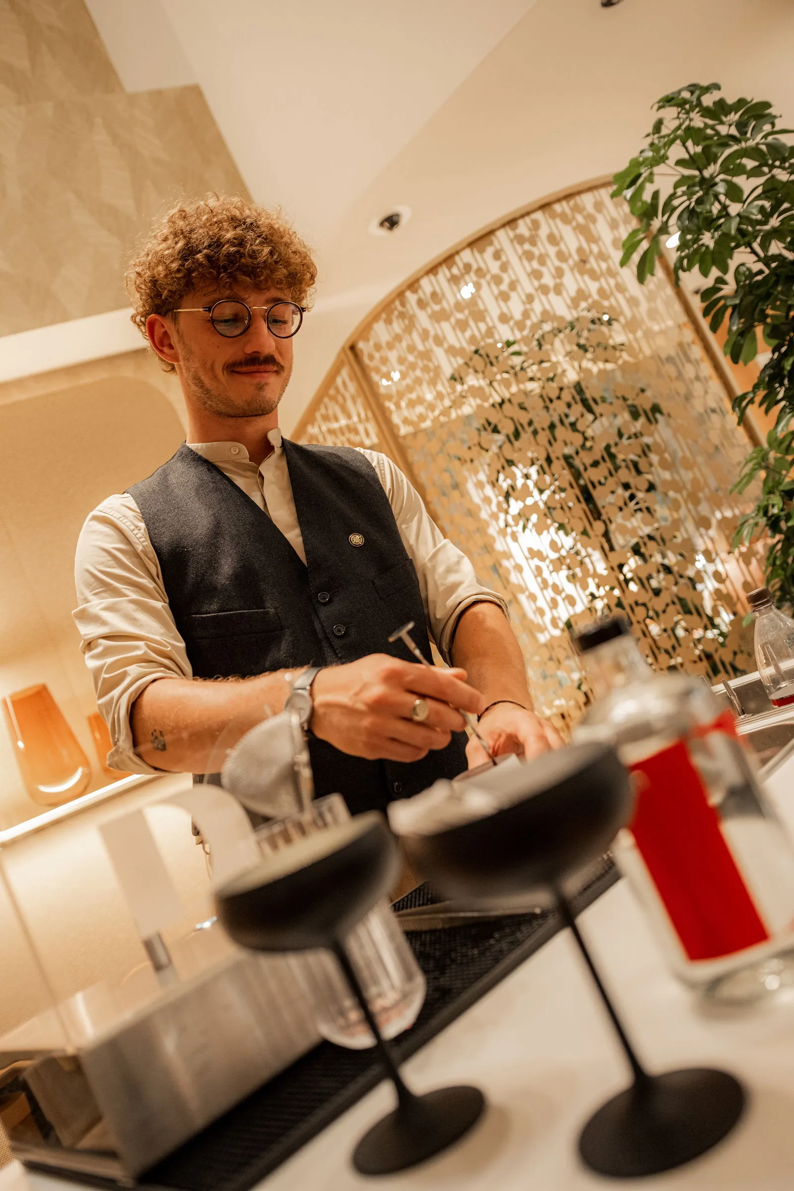 Zwei Coupettes im Vordergrund, während der Barkeeper beim Cocktailservice in Wien einen Drink veredelt