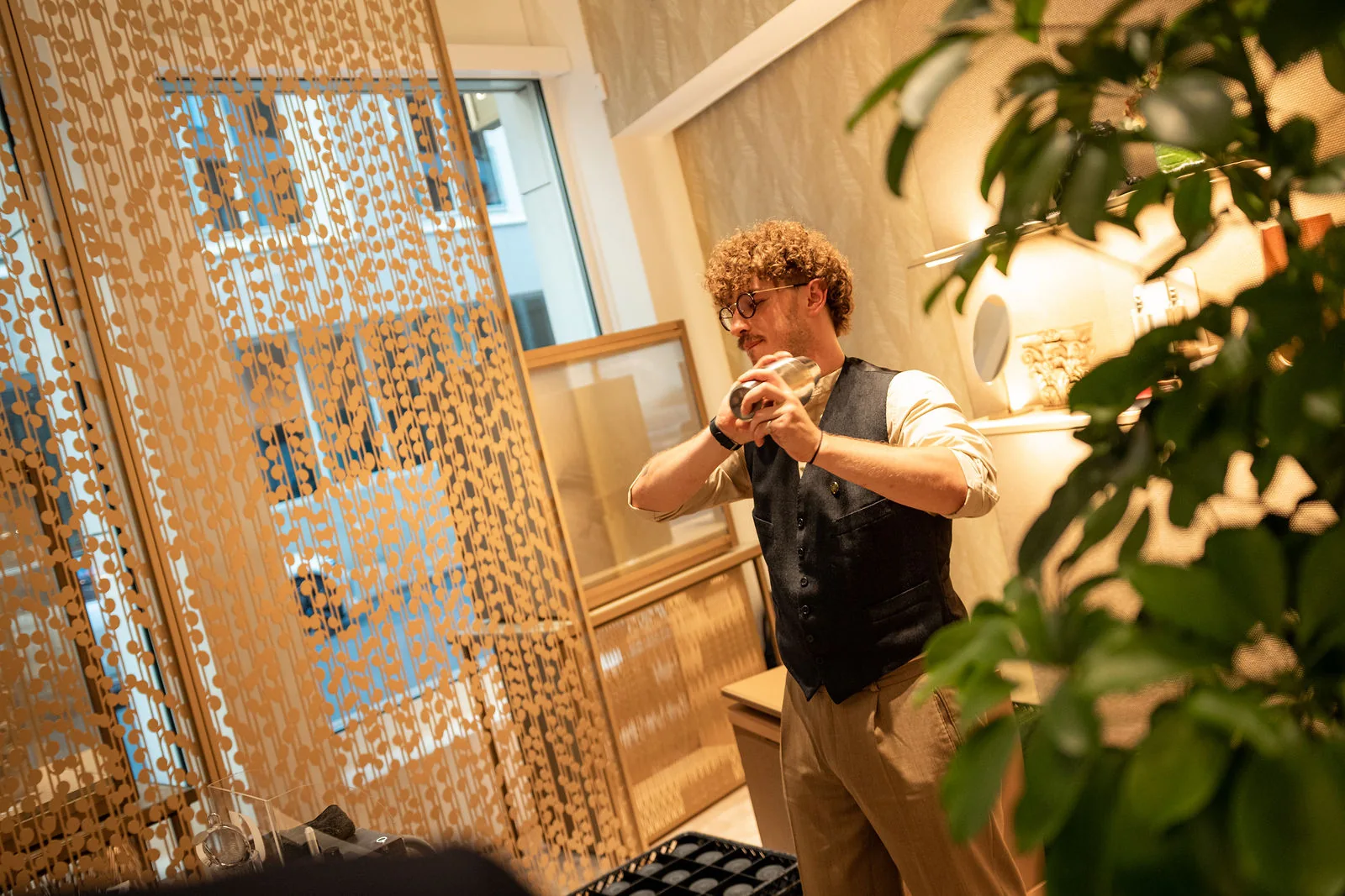 Ein mobiler Barkeeper in Wien bereitet vor einem Paravent und einer Grünpflanze einen Drink zu