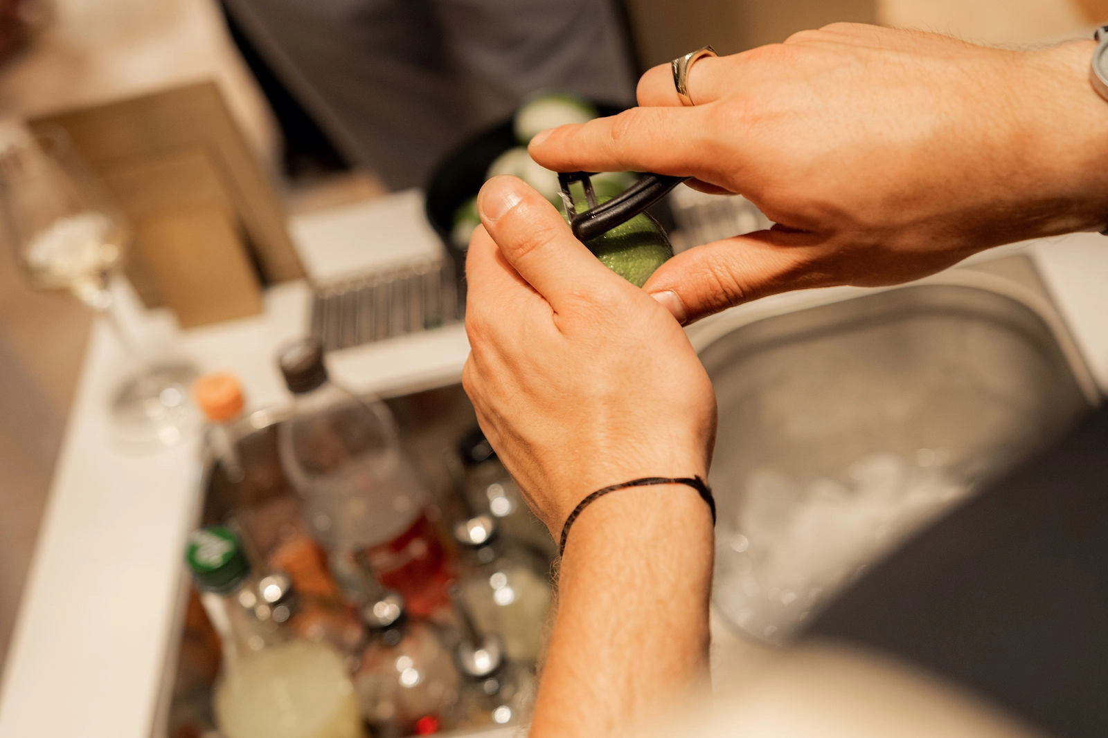 Über dem Eisfach halten Hände eine Gurkenscheibe als Garnitur an unserer Event-Bar in Wien
