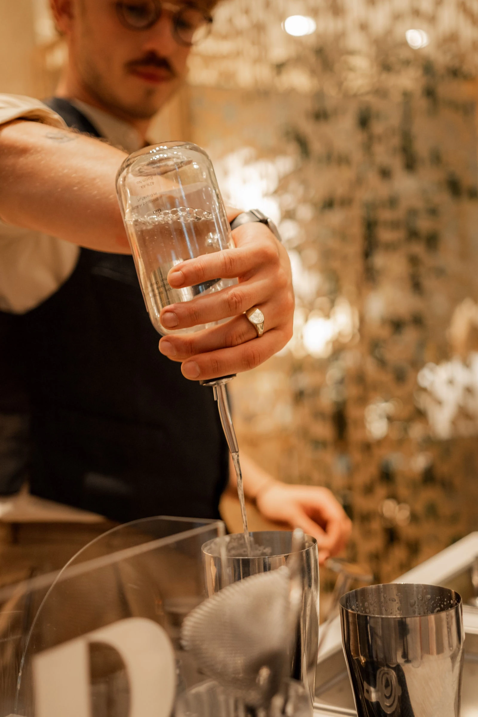 Nahaufnahme einer Hand, die aus einer Flasche in ein Glas an unserer Cocktailbar in Wien eingießt