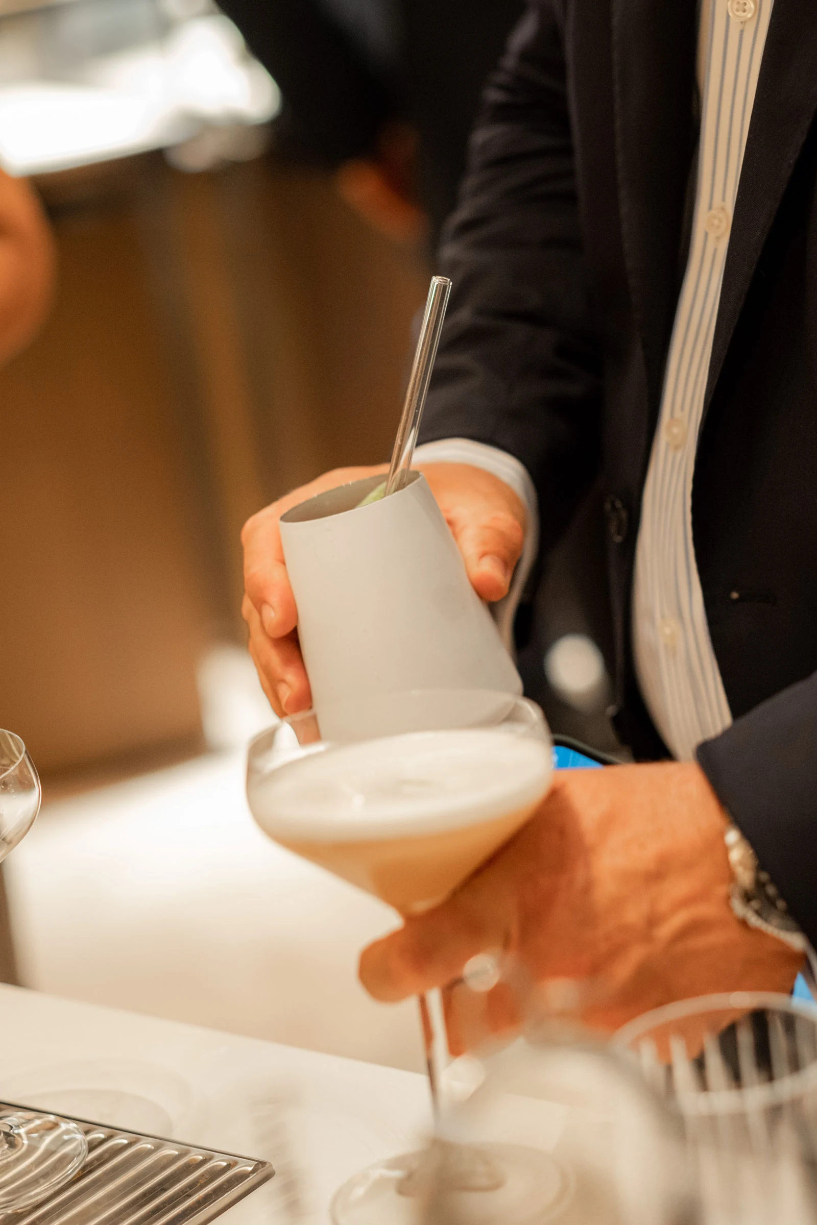 Aus dem Shaker fließt ein Cocktail mit feiner Schaumkrone in eine Coupette beim Store-Event in Wien